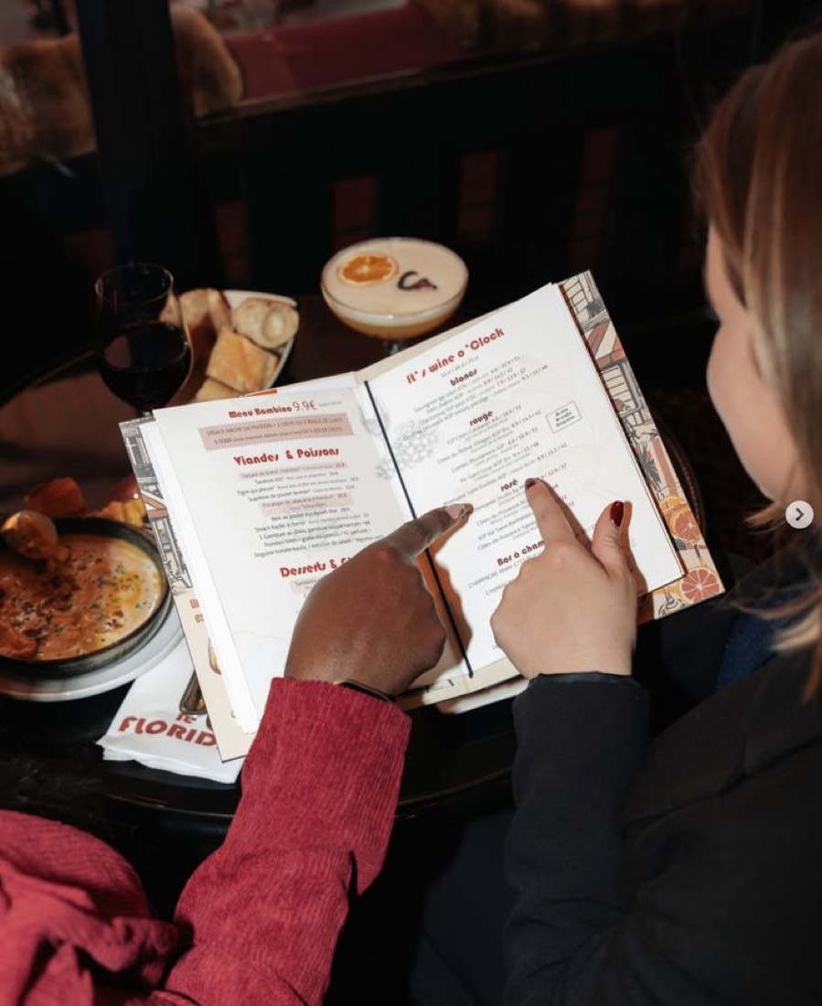 A guest reads a paper menu at a restaurant table, unrecognised by the venue
